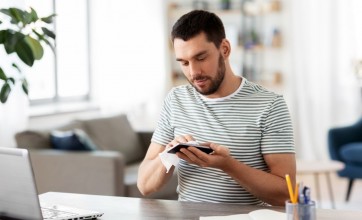 Office worker using disinfectant wipes on his device